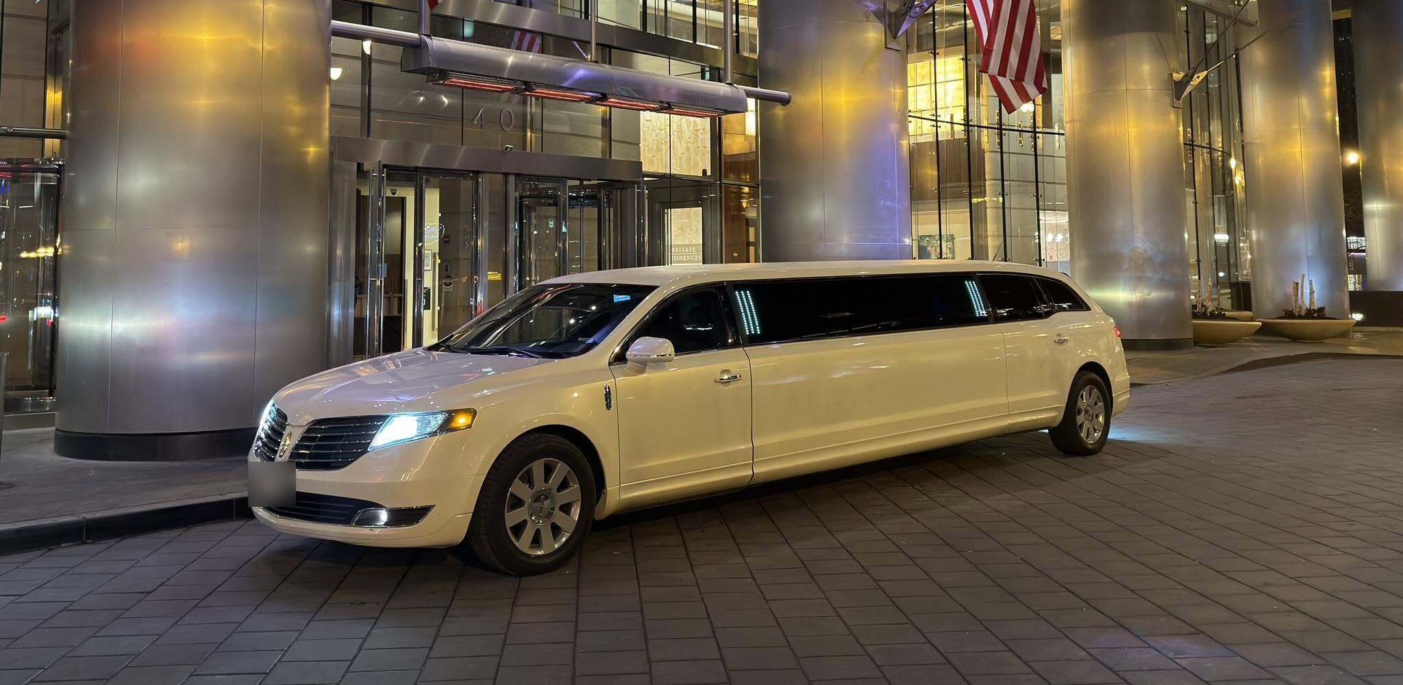 The white J Class stretch limousine parked outside a downtown Chicago hotel at night